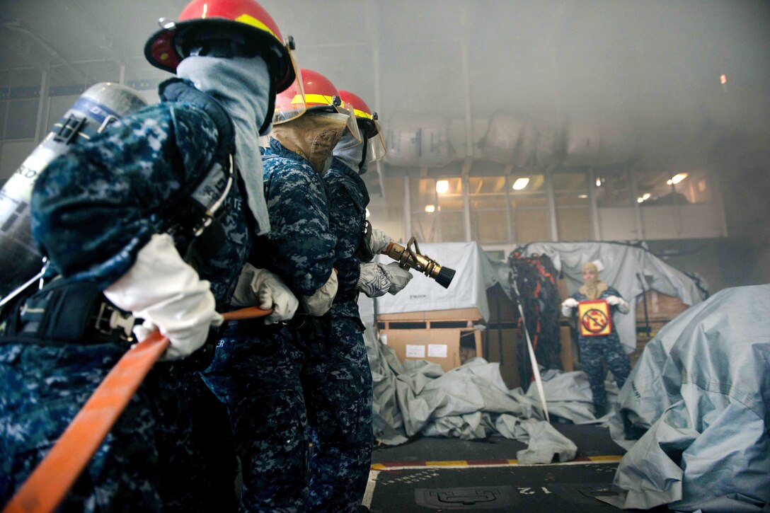 Sailors fight a simulated fire in the hangar bay during a general quarters drill