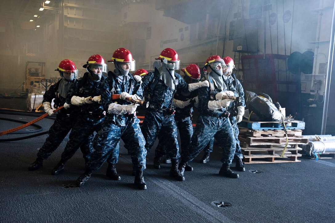 Sailors are instructed on proper firefighting techniques in the hangar bay during a general quarters drill.