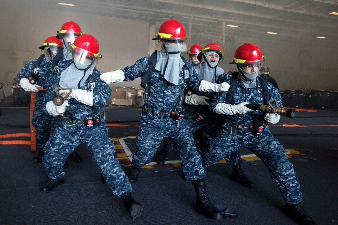 Sailors fight a simulated fire in the hangar bay during a general quarters drill.