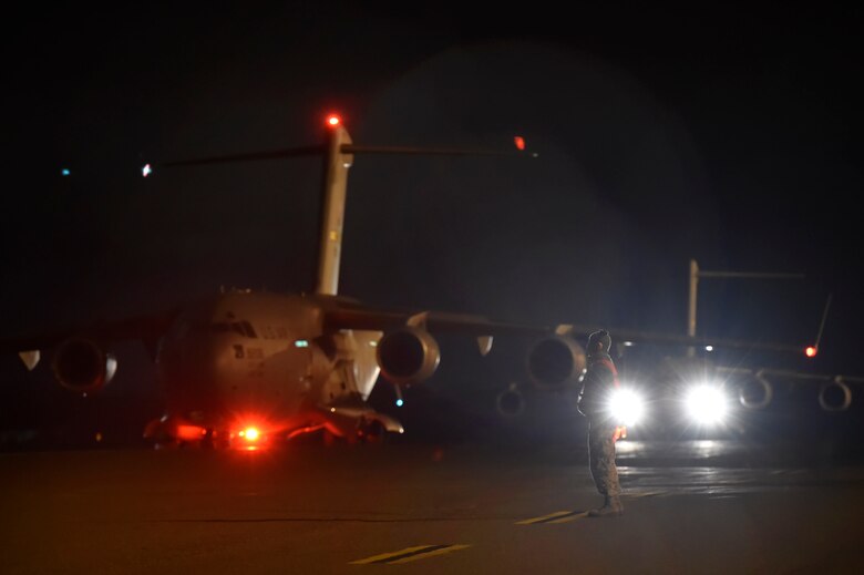 Airman 1st Class Kevin Schreiber, 437th Aircraft Maintenance Squadron crew chief, prepares to marshal a C-17 Globemaster during a Joint Forcible Entry training event in support of the U.S. Air Force Weapons School Integration phase here, Dec. 9. Thirty seven C-17s, 21 C-130 Hercules and 120 U.S. Army paratroopers participated in the mobility portion of the WSINT phase during a simulated mass JFE event over a contested target on a range near Nellis Air Force Base, Nev. The event is designed to teach Airmen how to get safely to their target and direct airpower and follow-on forces to that target.