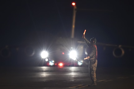 Airman 1st Class Kevin Schreiber, 437th Aircraft Maintenance Squadron crew chief, marshals a C-17 Globemaster during a Joint Forcible Entry training event in support of the U.S. Air Force Weapons School Integration phase here, Dec. 9. Thirty seven C-17s, 21 C-130 Hercules and 120 U.S. Army paratroopers participated in the mobility portion of the WSINT phase during a simulated mass JFE event over a contested target on a range near Nellis Air Force Base, Nev. The event is designed to teach Airmen how to get safely to their target and direct airpower and follow-on forces to that target.