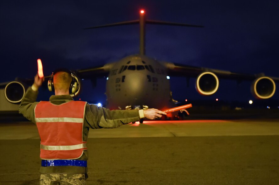 Airman 1st Class Logan Mueller, 437th Aircraft Maintenance Squadron crew chief, marshals a C-17 Globemaster during a Joint Forcible Entry training event in support of the U.S. Air Force Weapons School Integration phase here, Dec. 9. Thirty seven C-17s, 21 C-130 Hercules and 120 U.S. Army paratroopers participated in the mobility portion of the WSINT phase during a simulated mass JFE event over a contested target on a range near Nellis Air Force Base, Nev. The event is designed to teach Airmen how to get safely to their target and direct airpower and follow-on forces to that target.