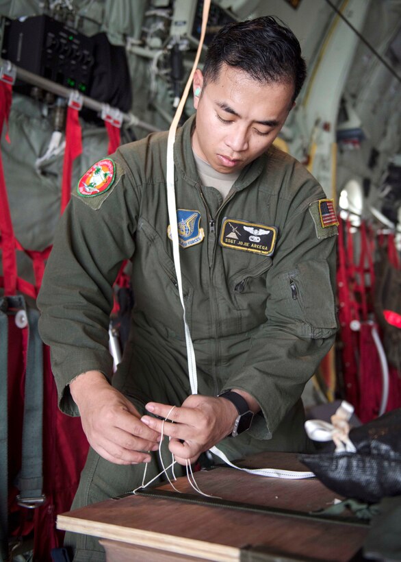 Air Force Staff Sgt. Jojie Arcega ties down practice bundles inside a C-130J Super Hercules