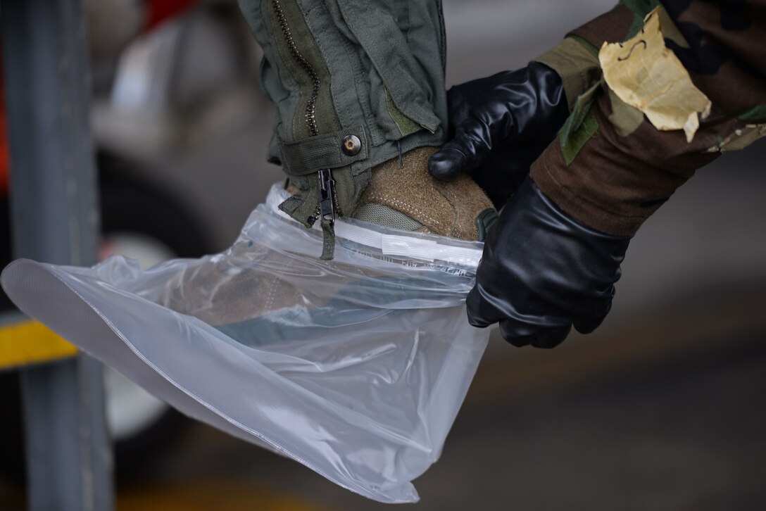 U.S. Air Force Senior Airman Delvion Wilborne, 20th Aircraft Maintenance Squadron 79th Aircraft Maintenance Unit tactical aircraft maintainer, assists 1st Lieutenant Robert Grochalski, 79th Fighter Squadron pilot, into the proper mission-oriented protective posture gear during an exercise at Shaw Air Force Base, S.C., Dec. 7, 2017.
