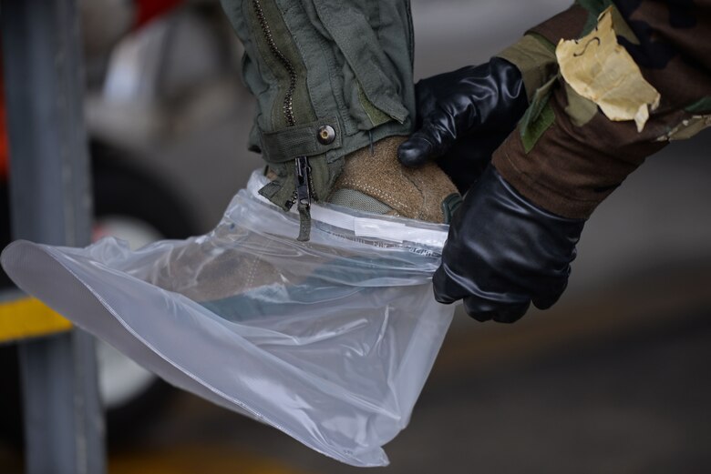U.S. Air Force Senior Airman Delvion Wilborne, 20th Aircraft Maintenance Squadron 79th Aircraft Maintenance Unit tactical aircraft maintainer, assists 1st Lieutenant Robert Grochalski, 79th Fighter Squadron pilot, into the proper mission-oriented protective posture gear during an exercise at Shaw Air Force Base, S.C., Dec. 7, 2017.