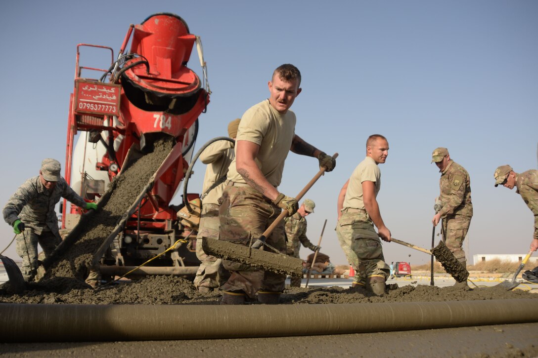 Service members pour concrete for a runway.