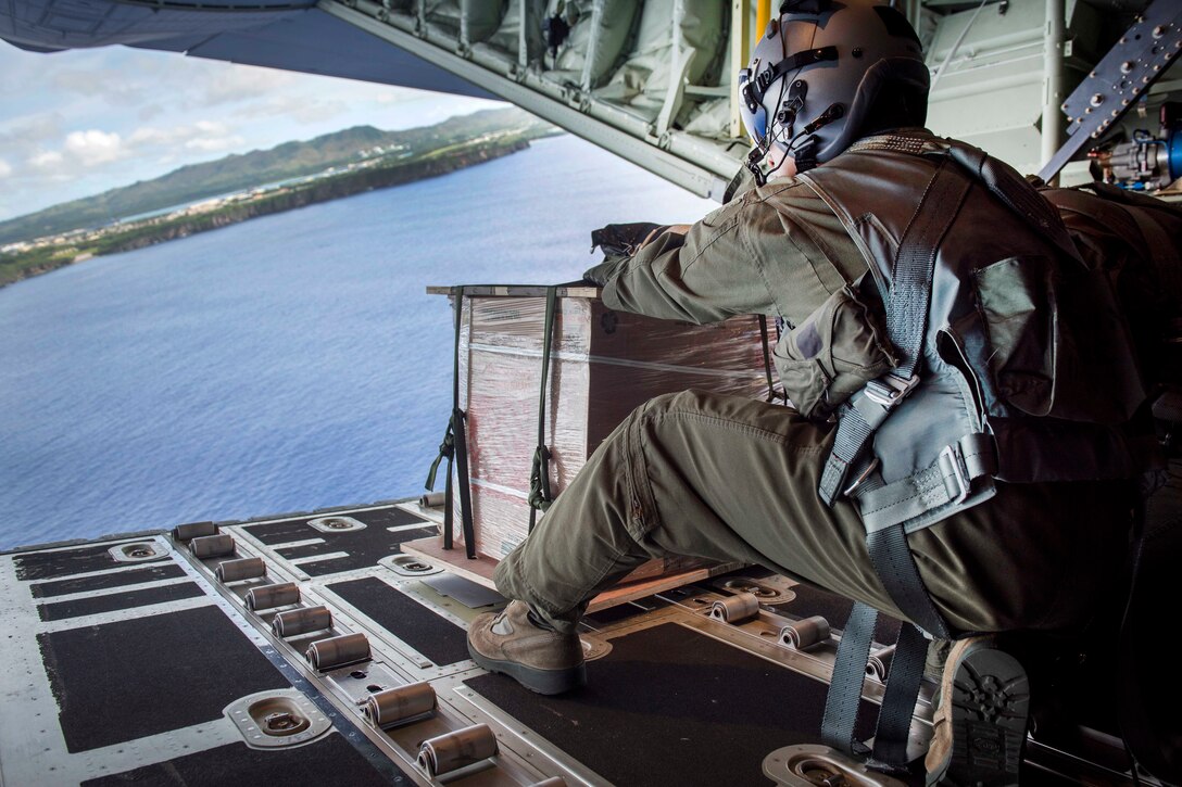Air Force Staff Sgt. Jojie Arcega pushes a practice bundle out from a C-130J Super Hercules aircraft.