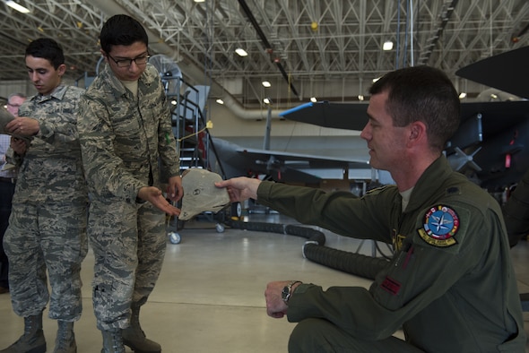 An Airman holds a piece of shrapnel from an advanced medium-range air-to-air missile.