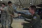 An Airman holds a piece of shrapnel from an advanced medium-range air-to-air missile.