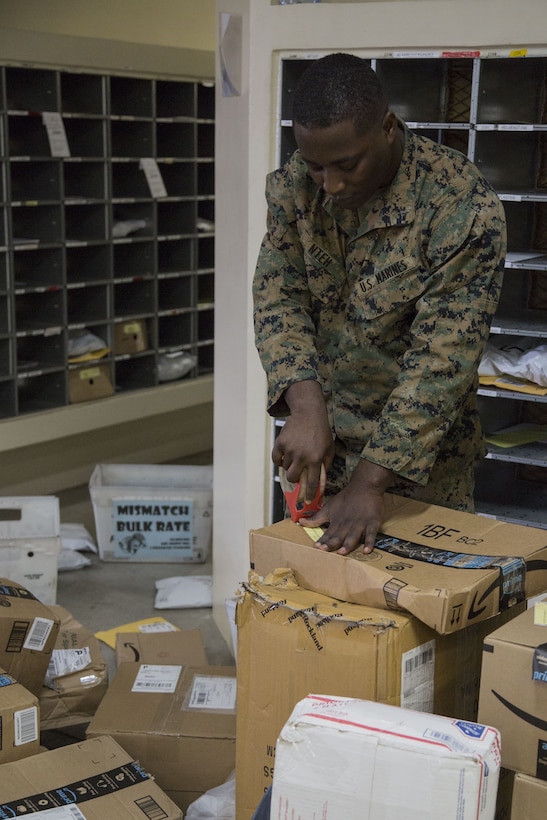 CAMP FOSTER, OKINAWA, Japan – Lance Cpl. Kinglsey Nteh reinforces the tape on delivered packages Dec. 12 at the Camp Foster Post Office aboard Camp Foster, Okinawa, Japan.