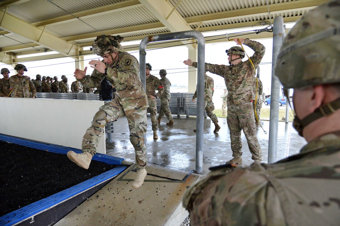 Soldiers practice going through an aircraft door on the ground.