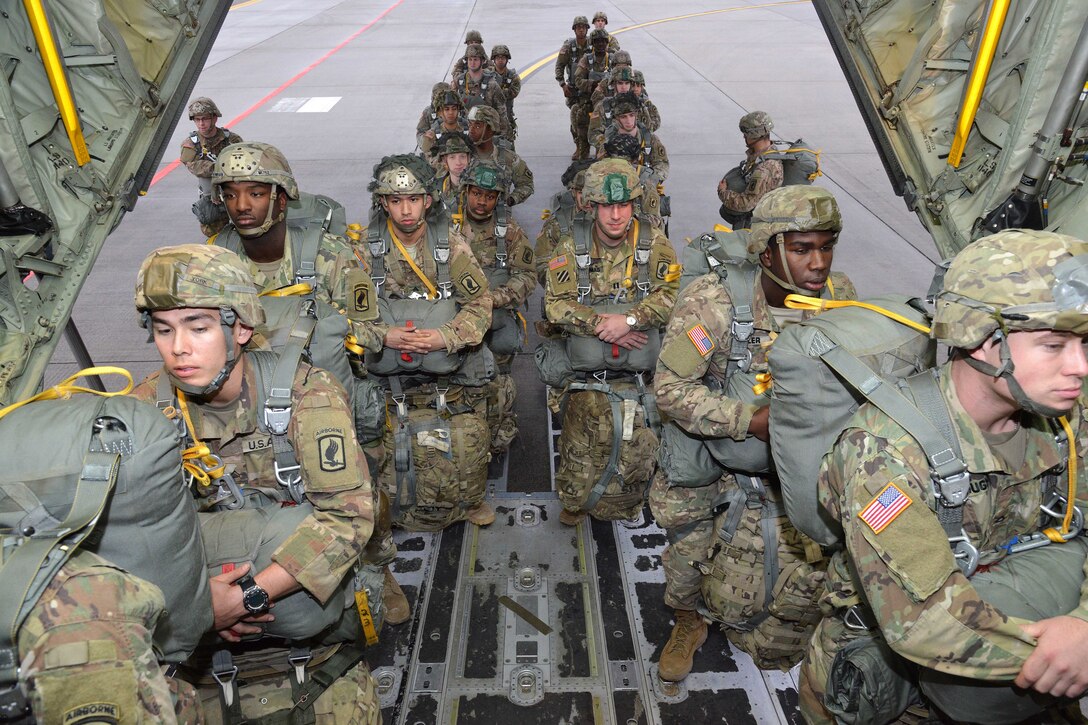 A line of soldiers walk up the ramp into an aircraft.