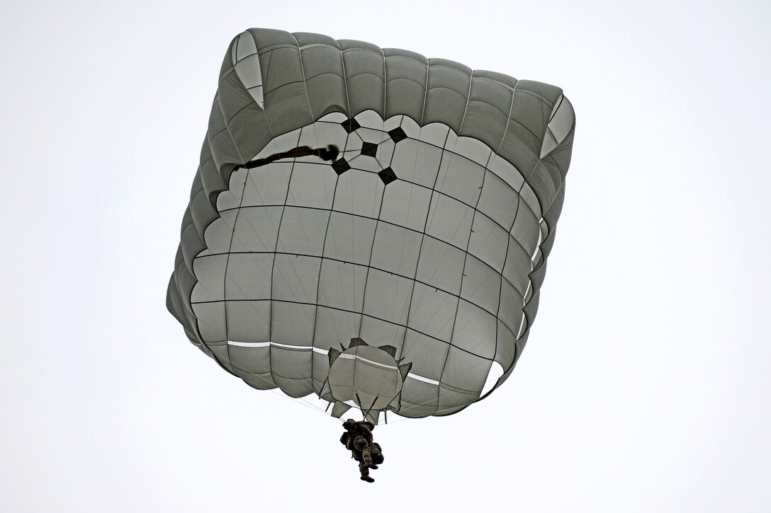 A soldier drifts to the ground using a parachute.