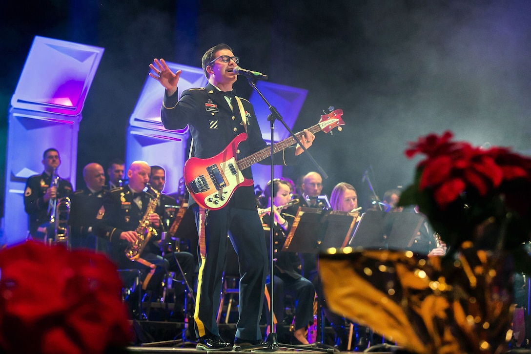 A soldier performs a song while playing the guitar during a holiday concert.
