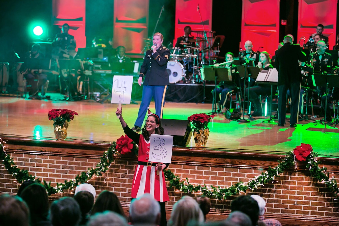 Army Sgt. Amy Mahoney sings 12 Days of Christmas with the help of elves during the Army Materiel Command's band holiday concert.