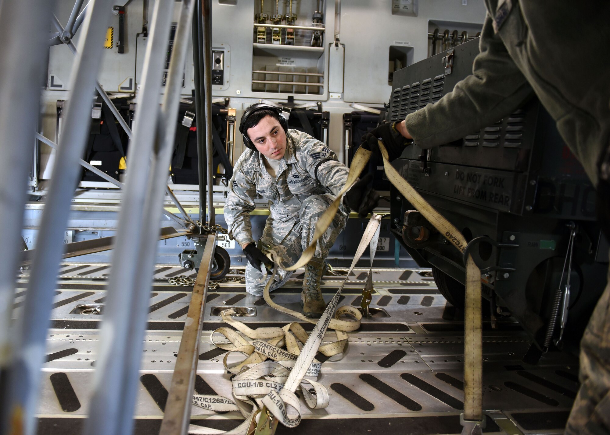 Senior Airman Daniel Romero, 62nd Aerial Port Squadron air transportation, secures cargo in preparation for airlift during a mobility exercise, Dec. 1, 2017 on the McChord Field flightline at Joint Base Lewis-McChord, Wash. The exercise was intended to hone the ability of 62nd Airlift Wing and 627th Air Base Group Airmen to deploy forces and cargo anywhere, anytime utilizing global airlift. (U.S. Air Force photo by Staff Sgt. Whitney Taylor)
