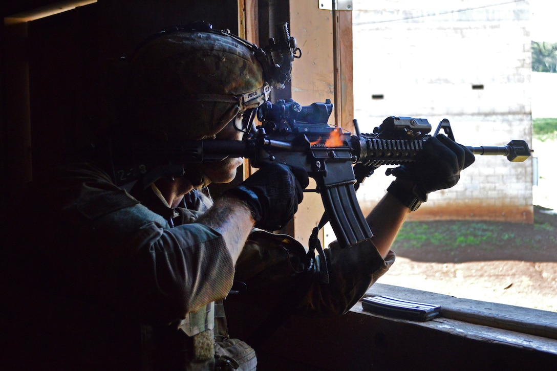A soldier fires a rifle out of a window.