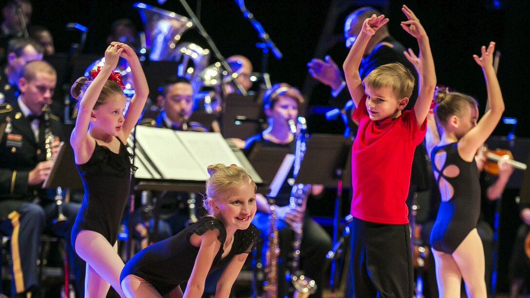 Children dance in front of Army musicians.