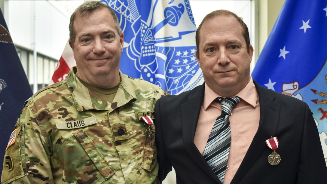 Two soldiers -- and brothers -- stand in front of flags after their retirement ceremony.