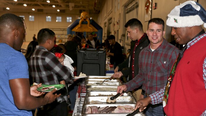 Lt. Col. Jeffrey Pelt and Sgt. Maj. Edward Hebron serve Marines during the Headquarters and Headquarters Squadron Christmas party aboard Marine Corps Recruit Depot Parris Island, Dec. 9. The party was held to foster unit cohesion and celebrate the upcoming holiday season. Pelt is the commanding officer and Hebron is the sergeant major of H&HS.