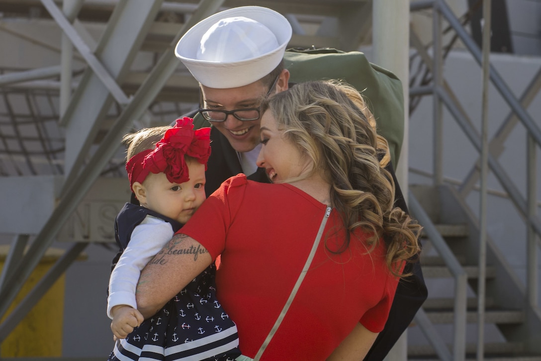 A sailor greets a woman and a child.