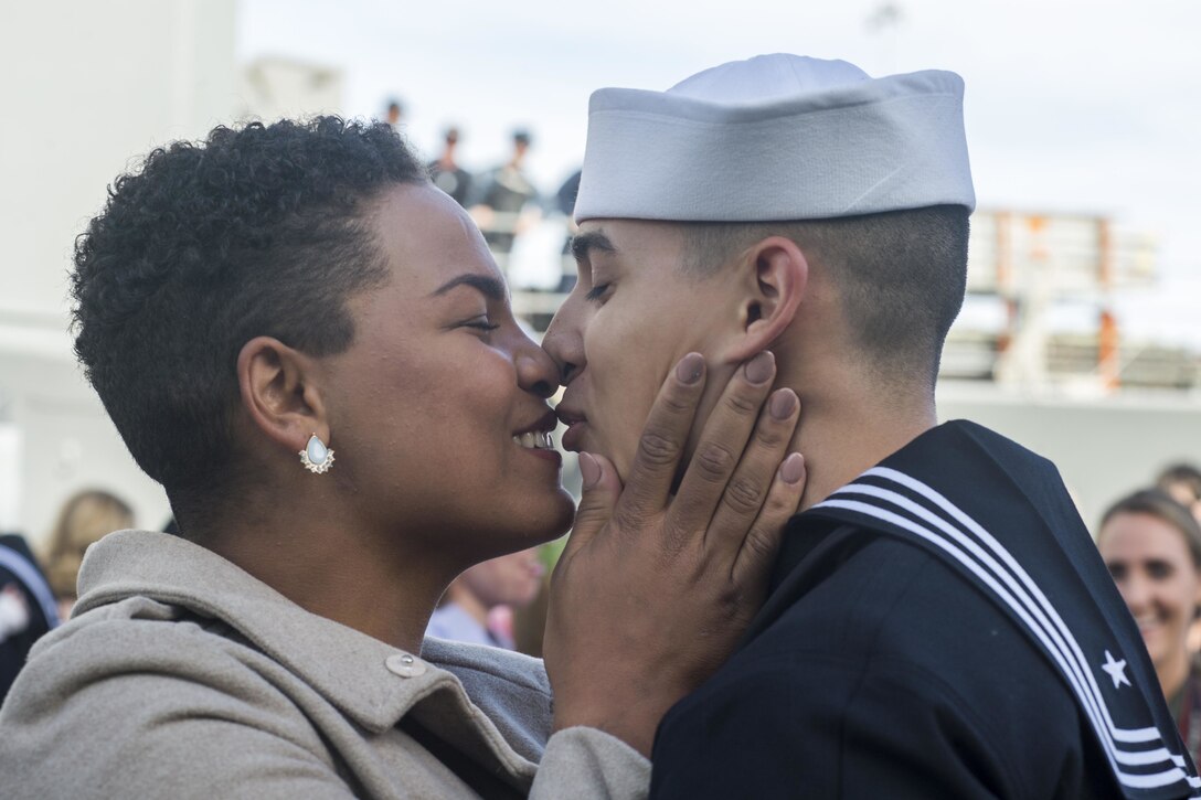A sailor kisses a woman.