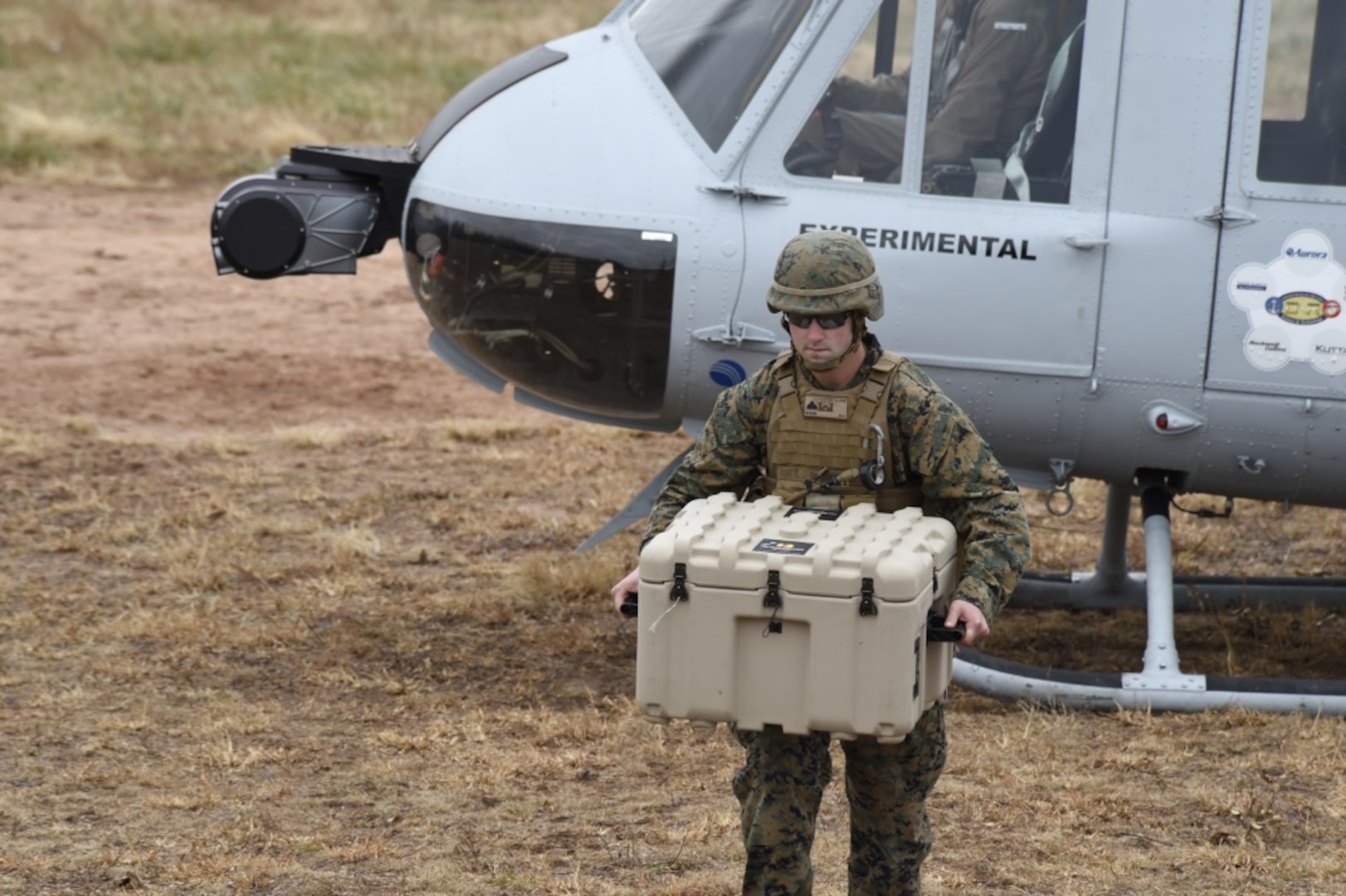 A Marine offloads cargo from a UH-1 Huey helicopter equipped with an Office of Naval Research-sponsored Autonomous Aerial Cargo/Utility System autonomy kit following a landing during final testing at Marine Corps Base Quantico, Va.