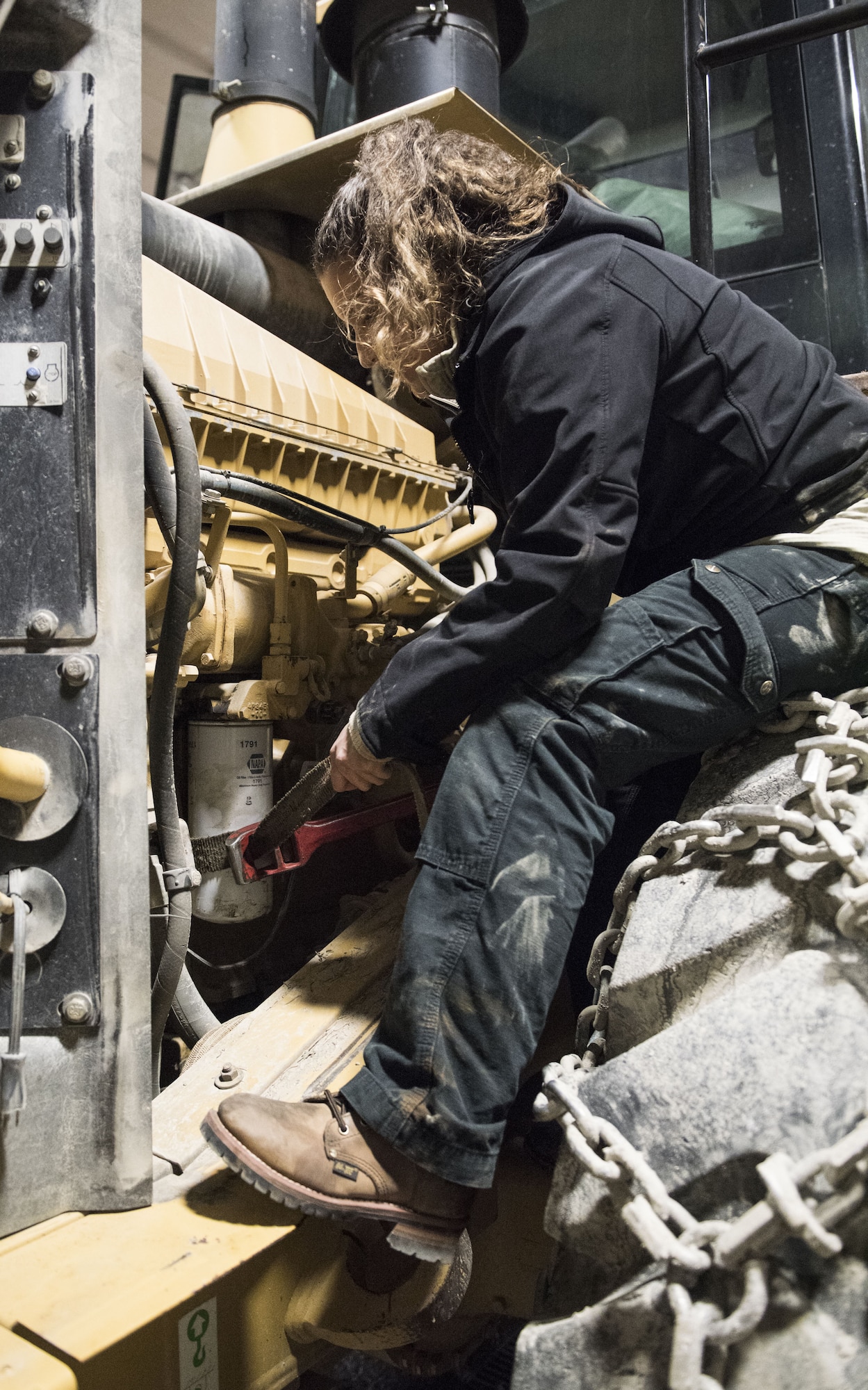 Senior Airman Jacqueline Cisne Morales, 336th Training Support Squadron vehicle maintenance journeyman, replaces an oil filter on a front end loader in Cusick, Washington, Dec. 7, 2017. Mechanics support the vehicle operators to enable their mission of clearing snow off of back roads in the National Forest. Clearing the snow in turn, enables the Air Force Survival School Airmen the ability drive to and from various training locations with minimal delay. (U.S. Air Force photo/Senior Airman Sean Campbell)