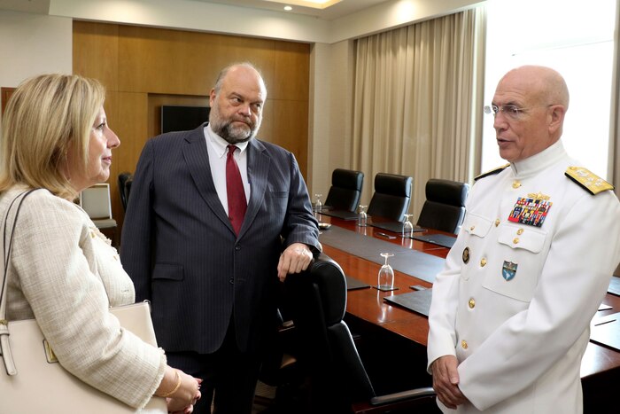 Three people talk in a conference room.