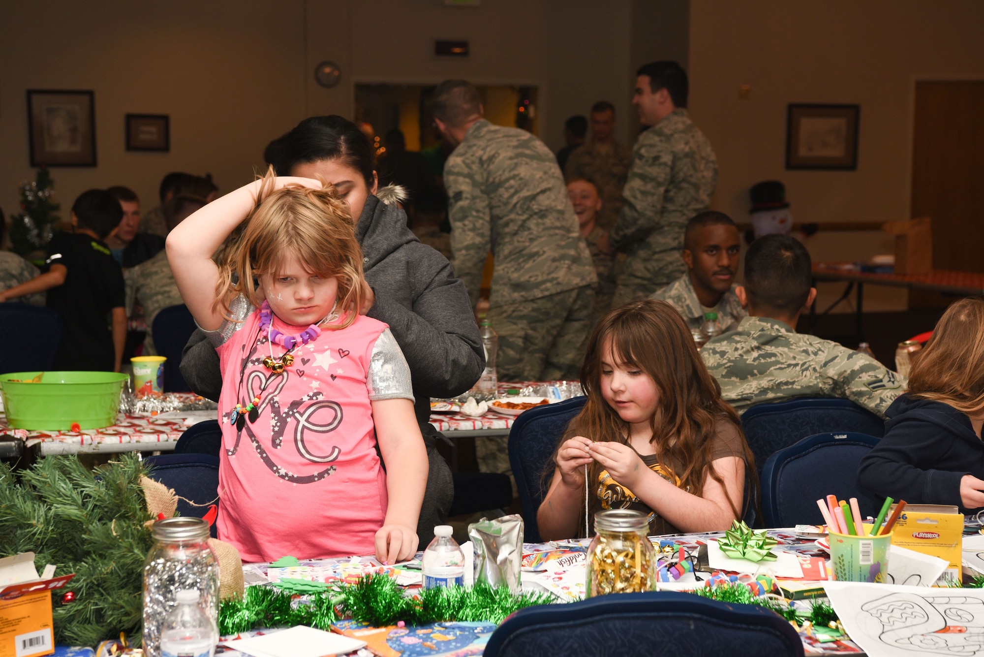 A child has her arts and crafts necklace tied on during Operation Provide Joy at F.E. Warren Air Force Base, Wyo., on Dec. 9, 2017. The event was a joint effort between the 321st Missile Squadron and the Salvation Army. The event was established to booster community partnership and to help local families in need get their children into the holiday spirit. (U.S. Air Force photo by Airman 1st Class Abbigayle Wagner)