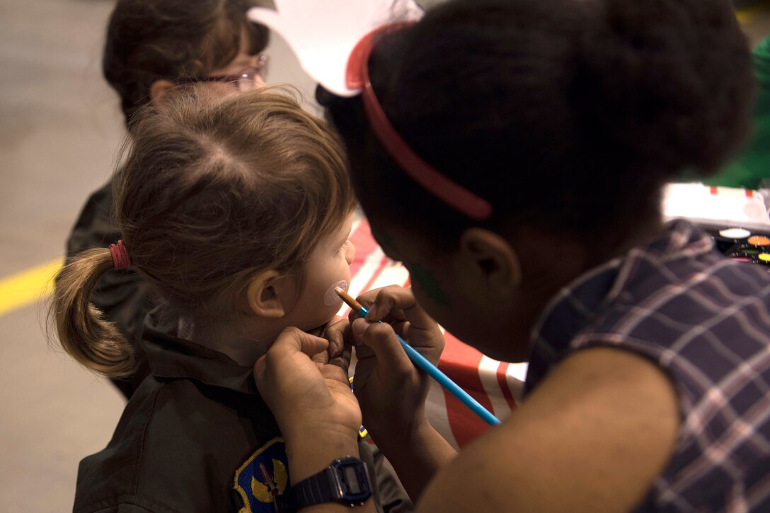 The child of a servicemember assigned to the 86th Airlift Wing has her face painted during the Rudolph the Red Nosed Herc event on Ramstein Air Base, Germany, Dec. 14, 2017. The event included bounce houses, games for the children and a decorated U.S. Air Force C-130J Super Hercules. (U.S. Air Force photo by Senior Airman Devin M. Rumbaugh)