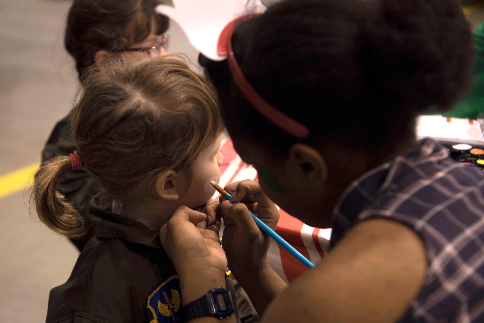 The child of a servicemember assigned to the 86th Airlift Wing has her face painted during the Rudolph the Red Nosed Herc event on Ramstein Air Base, Germany, Dec. 14, 2017. The event included bounce houses, games for the children and a decorated U.S. Air Force C-130J Super Hercules. (U.S. Air Force photo by Senior Airman Devin M. Rumbaugh)