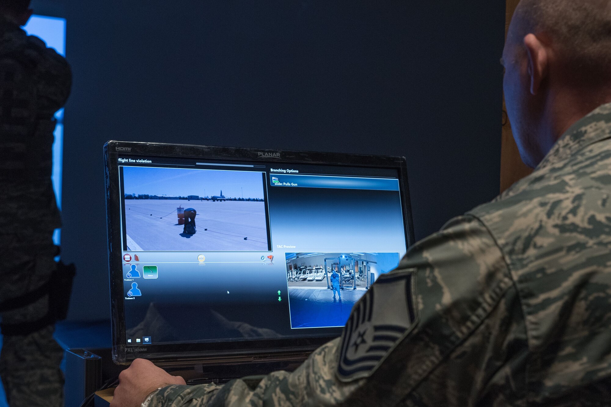 Master Sgt. Theodore Hemmah, a training manager for the 934th Security Forces Squadron, monitors fire team members as they participate in a scenario on the Multiple Interactive Learning Objectives simulator at the Minneapolis-St. Paul Air Reserve Station, Minn. on Dec. 14, 2017. The system includes software that allows instructors to create fully interactive video scenarios suited to their local missions. (U.S. Air Force photo by Master Sgt. Eric Amidon)