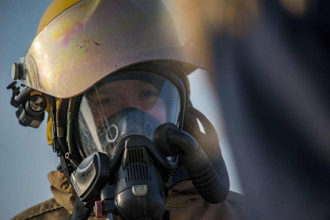 A firefighter looks at an object.