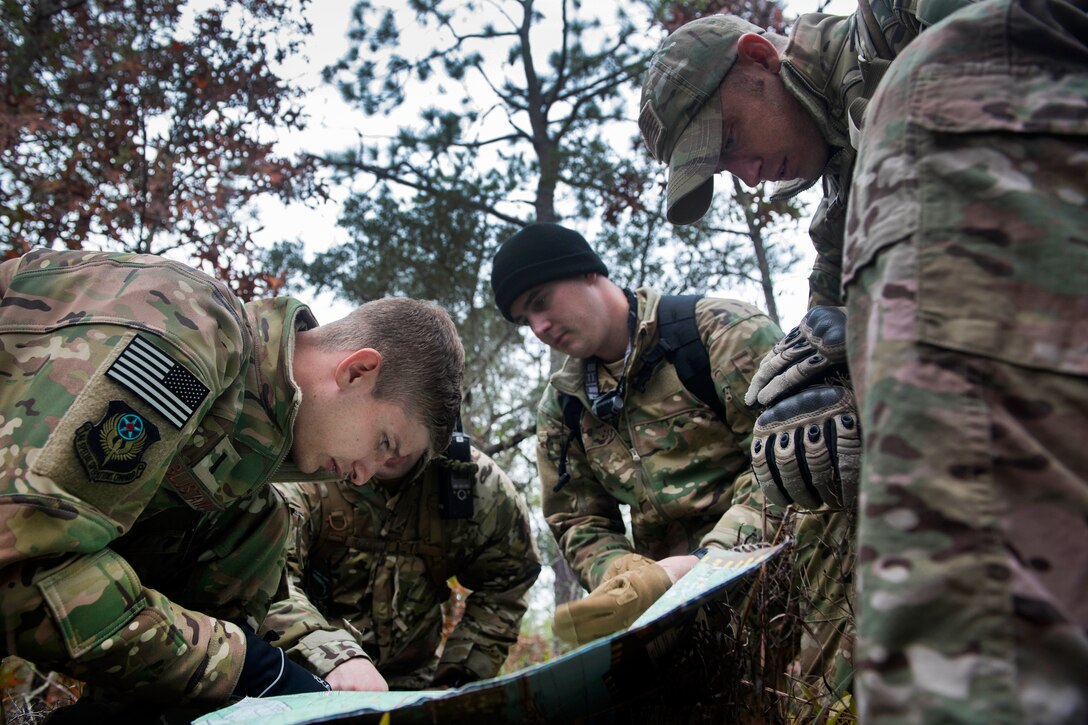 A group of airmen kneel over a map.