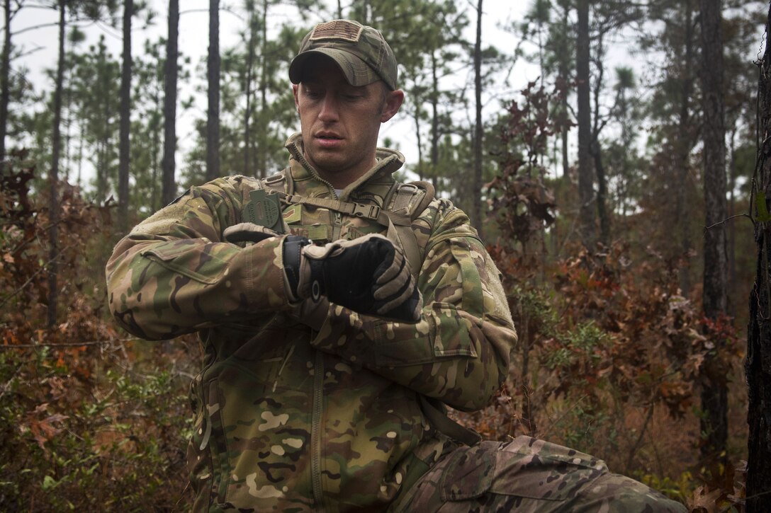 An airman checks his location on a compass attached to his wrist.