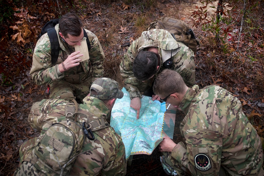 Four airmen kneel over a map.