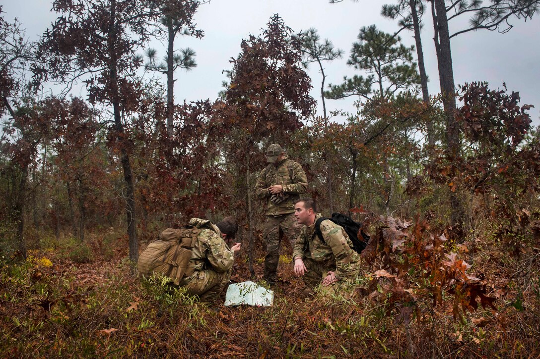 A group of airmen kneel in the brush.