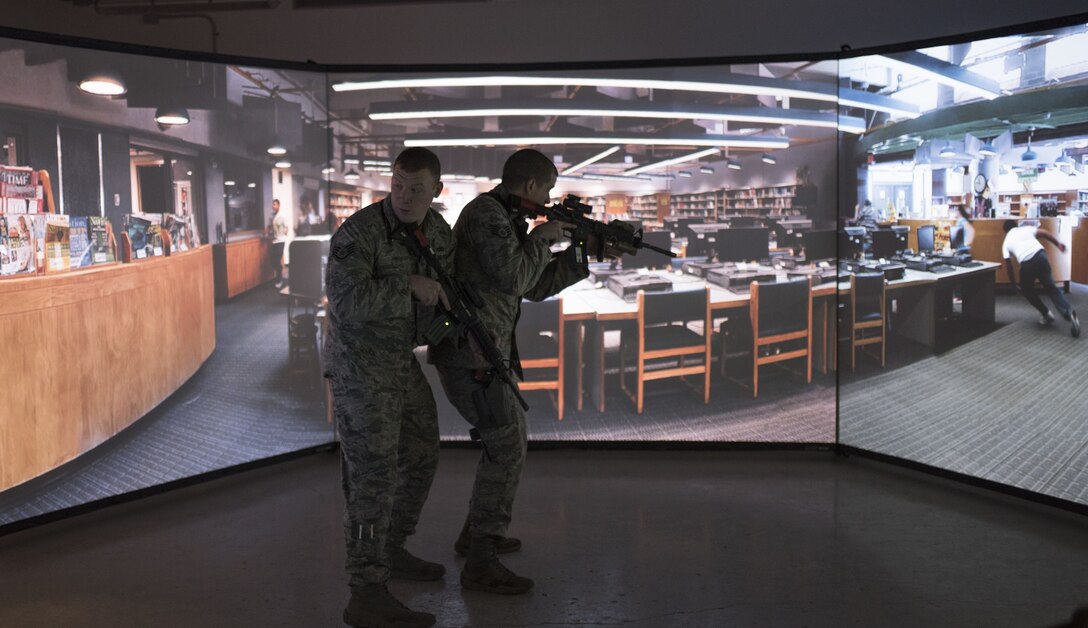 Staff Sgt. Tyler Frats, left, and Staff Sgt. Brian Walker, both from the 821st Security Forces Squadron, demonstrate an active shooter drill using a combat simulator at Thule Air Base, Greenland, Dec. 11, 2017 . With the base being so remote, the simulator allows for the Airmen to train regardless of the weather. (U.S. Air Force photo by Senior Airman Dennis Hoffman)