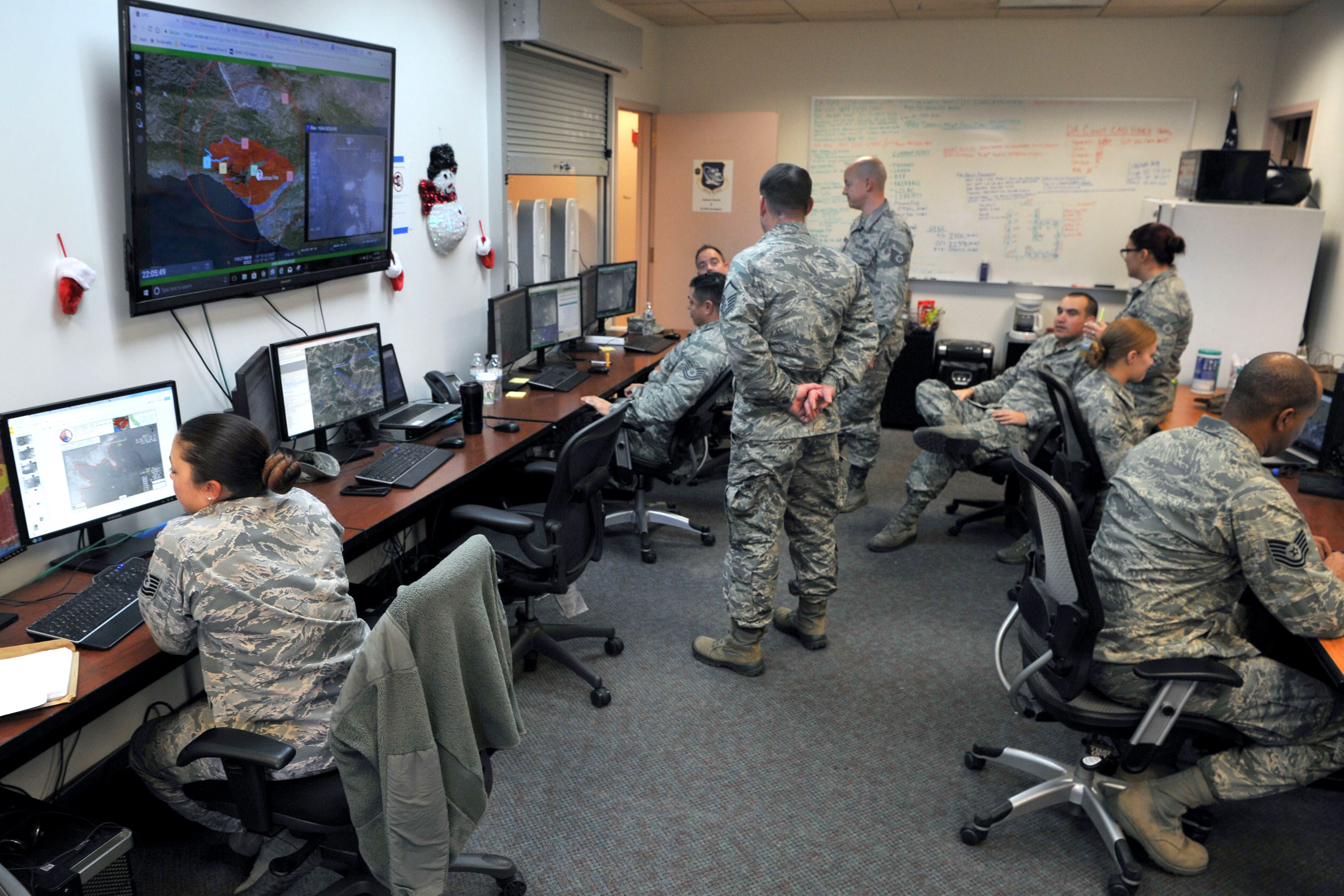 Airmen work on computers in an office.
