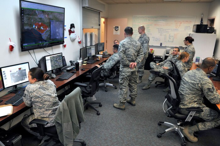 Airmen work in a room filled with computers