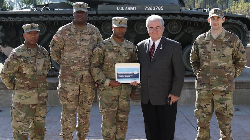 Four Soldiers and one civilian pose for photo with certificate.