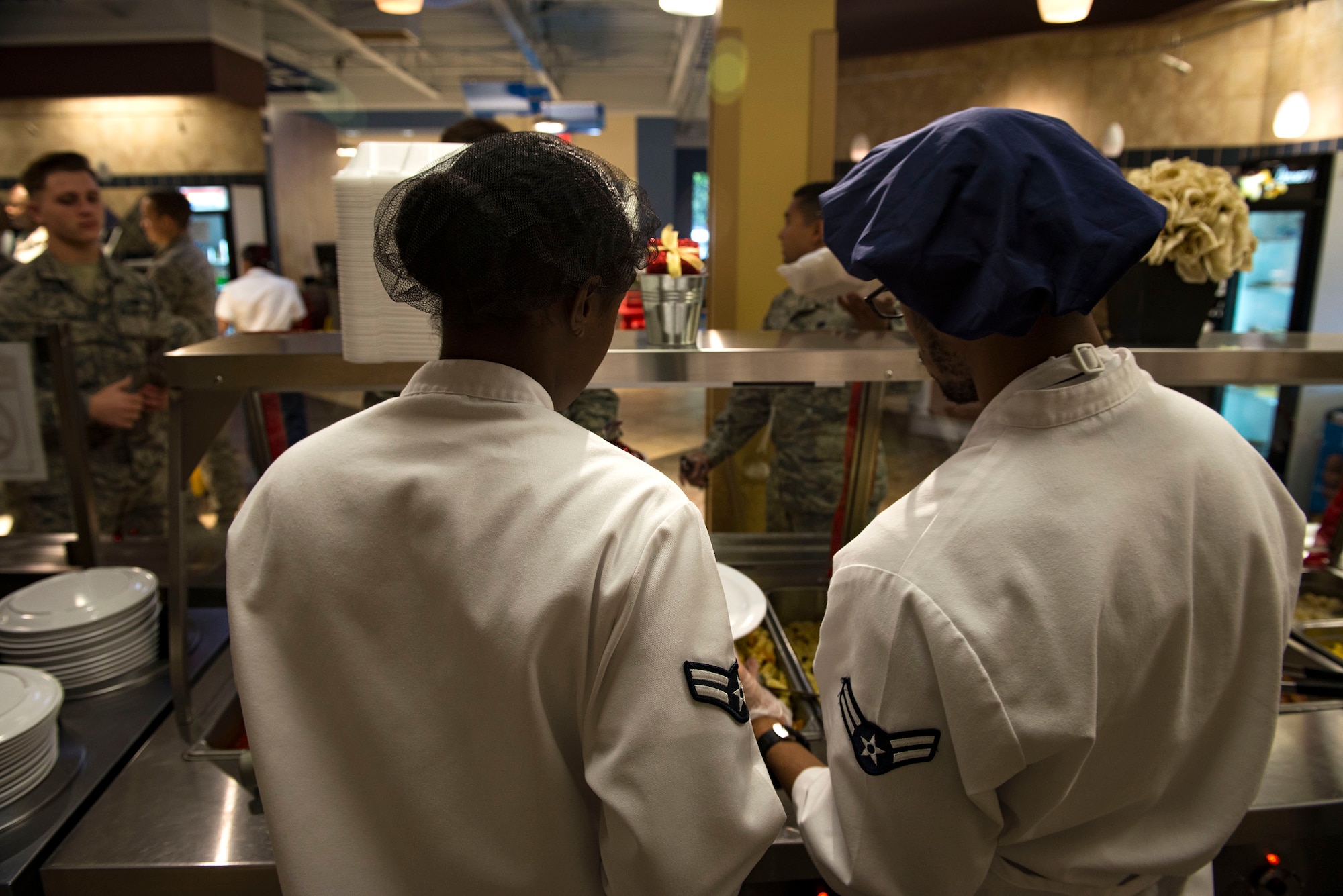 Airman 1st Class Ravin Collins, left, 23d Force Support Squadron food services journeyman, and Airman 1st Class Keven Fears, 23d FSS food services specialist, serve Airmen during lunch in the Georgia Pines Dining Facility (DFAC), Dec. 12, 2017, at Moody Air Force Base, Ga. Through teamwork, adaption and striving for excellence, the Georgia Pines DFAC Airmen are able to ensure Team Moody is fed and ready to finish the fight. (U.S. Air Force Base photo by Airman 1st Class Erick Requadt)