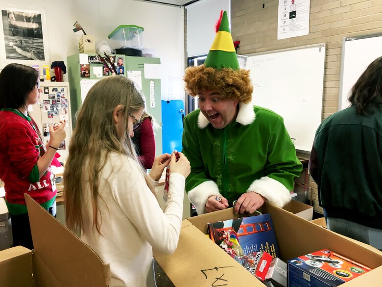 Buddy the Elf, played by Master Sgt. Daron Nelson, watches as Avonlea opens gifts during a Christmas party
