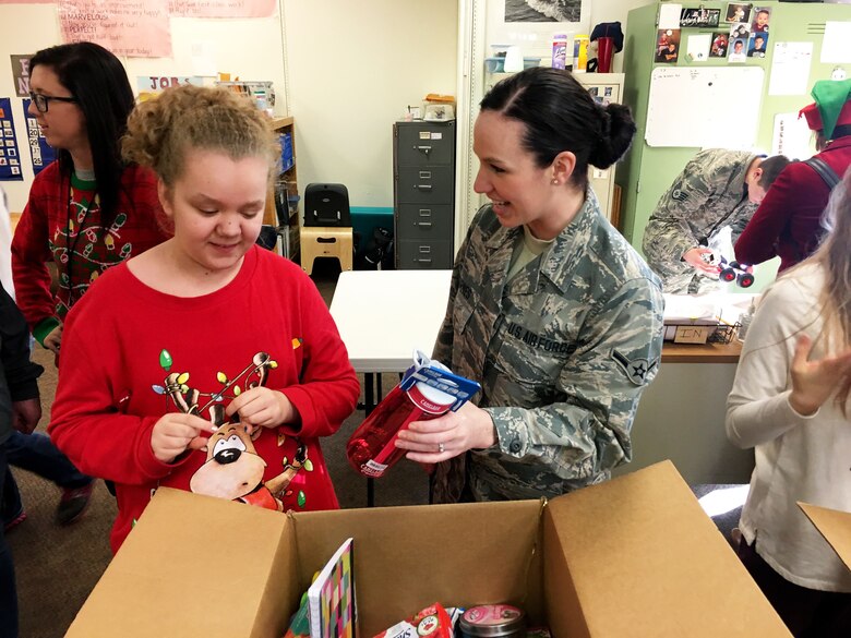 Airman Amy Barnes, 67th Aerial Port Squadron, helps Haylee unpack a box of gifts