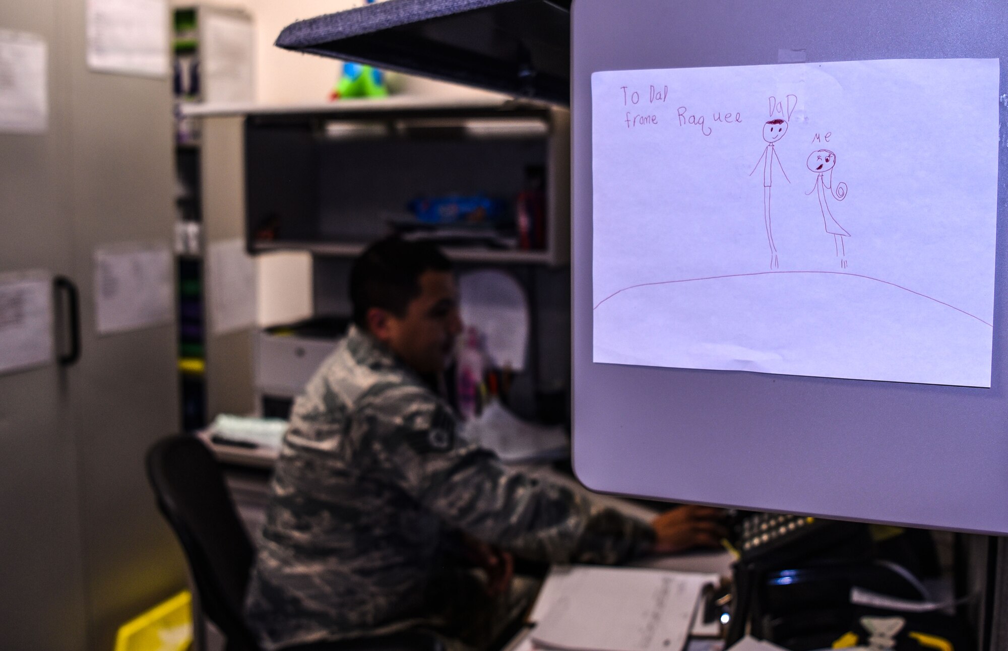 Staff Sgt. Miguel Guajardo, 90th Medical Group NCO in charge of logistics, works in his office in the dental clinic with a drawing from his child on the wall at F.E. Warren Air Force Base, Wyo., on Dec. 13, 2017. Miguel works with his wife in the clinic and they are proving it is possible to be successful together at home and work. Success for this couple means putting family first.
