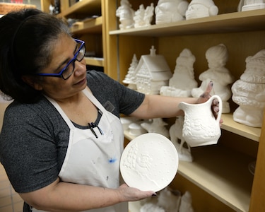 Evelyn Aslou, recreational assistant at the Polar Express Arts and Crafts Center, shows holiday themed sets of ceramics available to paint at Joint Base Elmendorf-Richardson, Alaska, Dec. 11, 2017. Recreational assistants are available to help set up supplies, answer questions, and offer expertise on craft projects at the Polar Express Arts and Crafts Center.