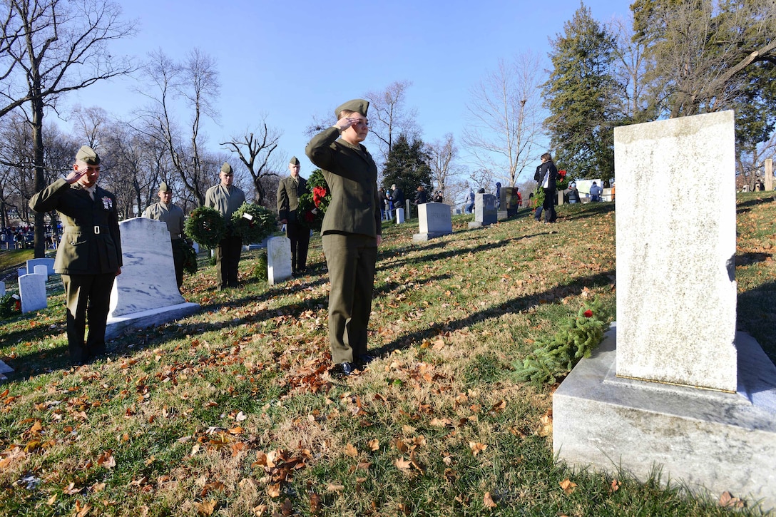 Marines salute grave markers in a cemetery.
