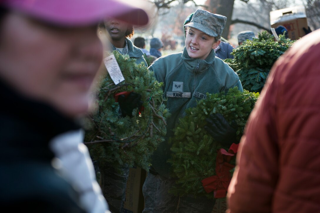 An airman hands wreaths to volunteers.