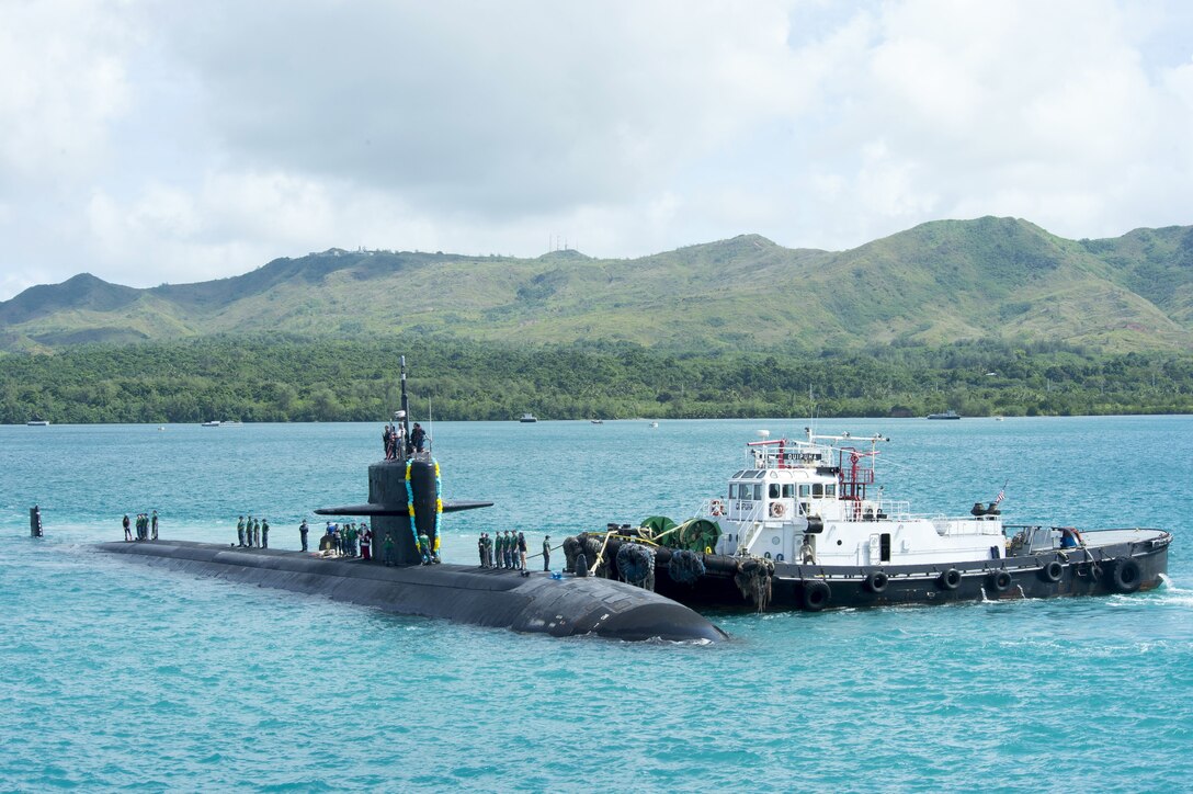 A boat and a submarine float in the water near one another.